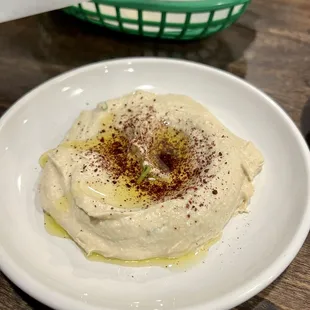 a plate of hummusle and a basket of bread