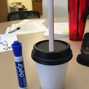 a plastic cup with a straw and a blue marker