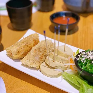 a plate of appetizers and a bowl of dipping sauce