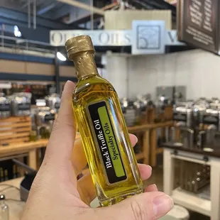 a hand holding a bottle of olive oil