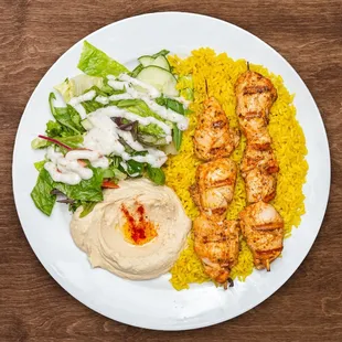 a white plate with chicken, rice, and salad