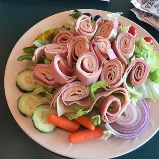 a plate of salad with ham and vegetables