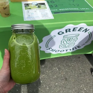 a person holding a jar of green smoothie