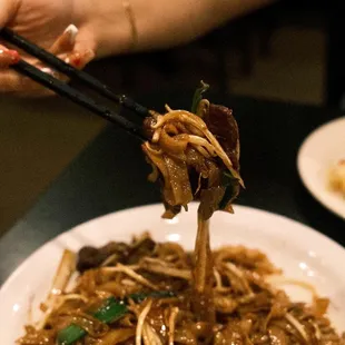a plate of noodles with chopsticks