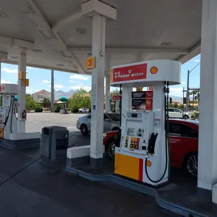 a gas station with a red car at the pump
