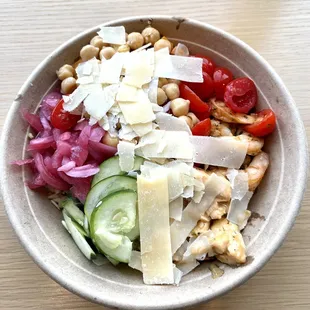 a bowl of salad with chickpeas, tomatoes, cucumbers, and parmesan cheese