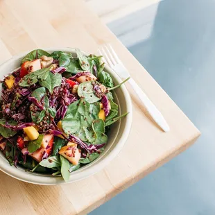 a bowl of salad on a wooden table