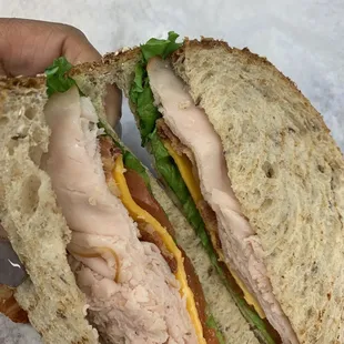 Smoked turkey and bacon on multigrain bread with cheddar cheese and lettuce and tomato