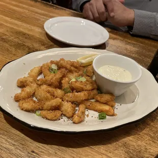 a plate of deep fried shrimp with a side of dipping sauce