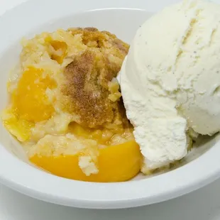 a bowl of ice cream and peach cobble