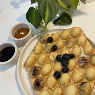 Blueberry bubble waffles with side of blueberry sauce and maple syrup