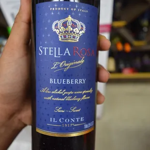 a hand holding a bottle of blueberry wine