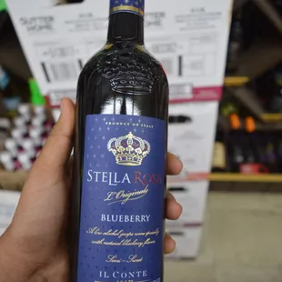 a hand holding a bottle of blueberry wine