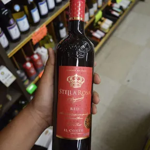 a hand holding a bottle of red wine