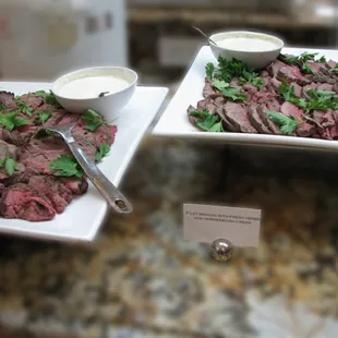 Platter of sliced filet mignon, fresh herbs and a horseradish cream on the side