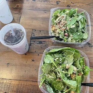 two plastic containers of salad on a wooden table