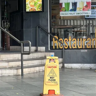 a caution wet floor sign in front of a restaurant
