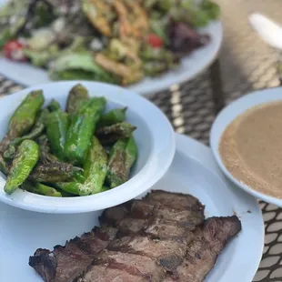 a plate of steak and a bowl of sauce