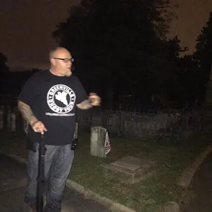 a man in a black t - shirt standing in a cemetery