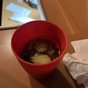 a red bowl of soup with pickles