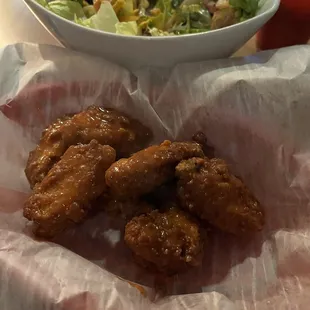 a basket of fried chicken and a bowl of salad