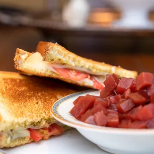 a grilled cheese sandwich and a bowl of chopped tomatoes