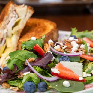 a plate of salad with a grilled cheese sandwich