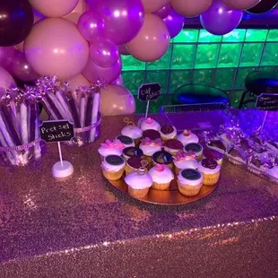 a table with cupcakes and balloons