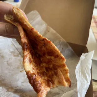 a hand holding a piece of pizza