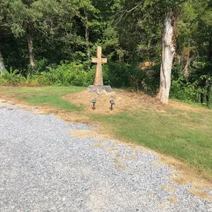 a cross in the middle of a gravel road