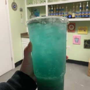 a person holding a cup of green liquid