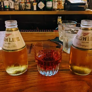 two bottles of beer and a glass of whiskey