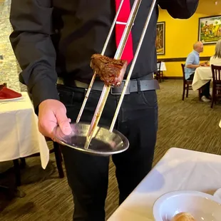 a man in a black shirt and red tie holding a plate of food