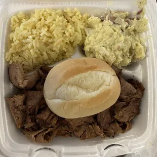 Brisket with rice and potato salad and a diner roll.