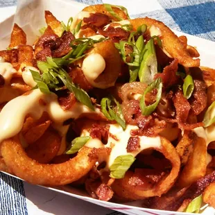 Loaded Fries- seasoned fries topped with queso cheese sauce, crispy bacon crumbles, and green onion