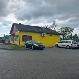two cars parked in front of a yellow building