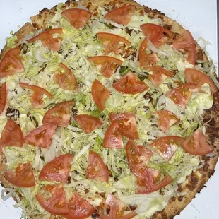 a pizza with tomatoes and lettuce