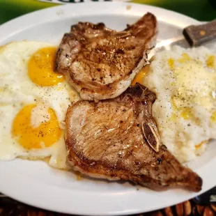 Pork chops, eggs, sunny side up and grits with added cheese
