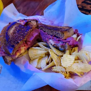 Reuben Sandwich with chips and a pickle spear