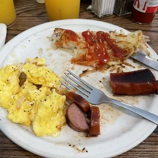 Breakfast plate with scrambled egg, smoked sausage, hash browns, and a biscuit.