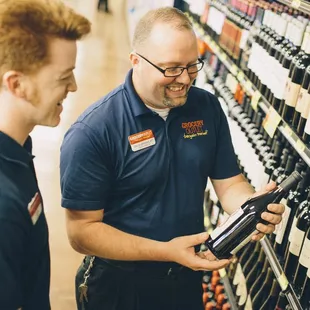 two men looking at bottles of wine