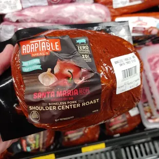 a person holding a ham wrapped in plastic wrap