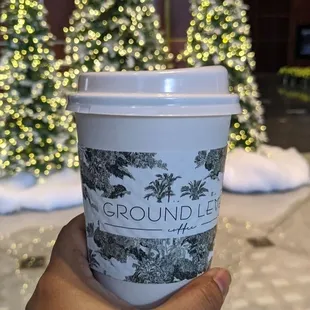 a hand holding a cup of ground level coffee
