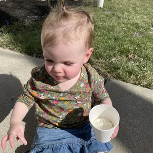 a toddler holding a cup of coffee