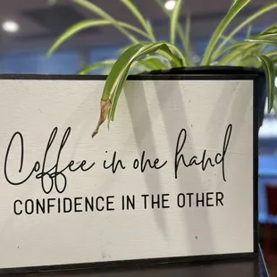 a sign that says coffee in the hand confidence in the other
