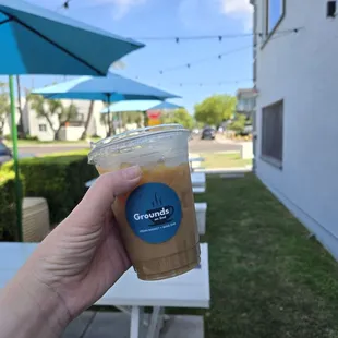 16oz iced coffee outside in the café&apos;s outdoor seating area.