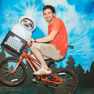 a man riding a bike with a robot in the basket
