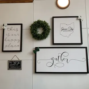 a wall with framed signs and wreaths