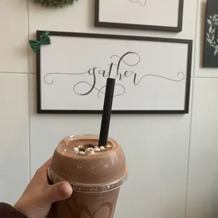 a hand holding a chocolate milkshake