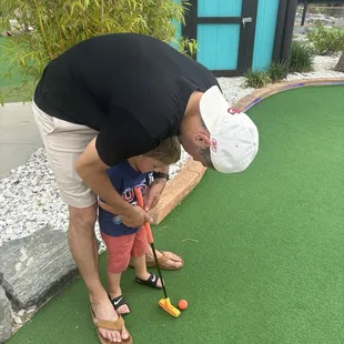 Daddy teaching our three year old how to hold a golf club